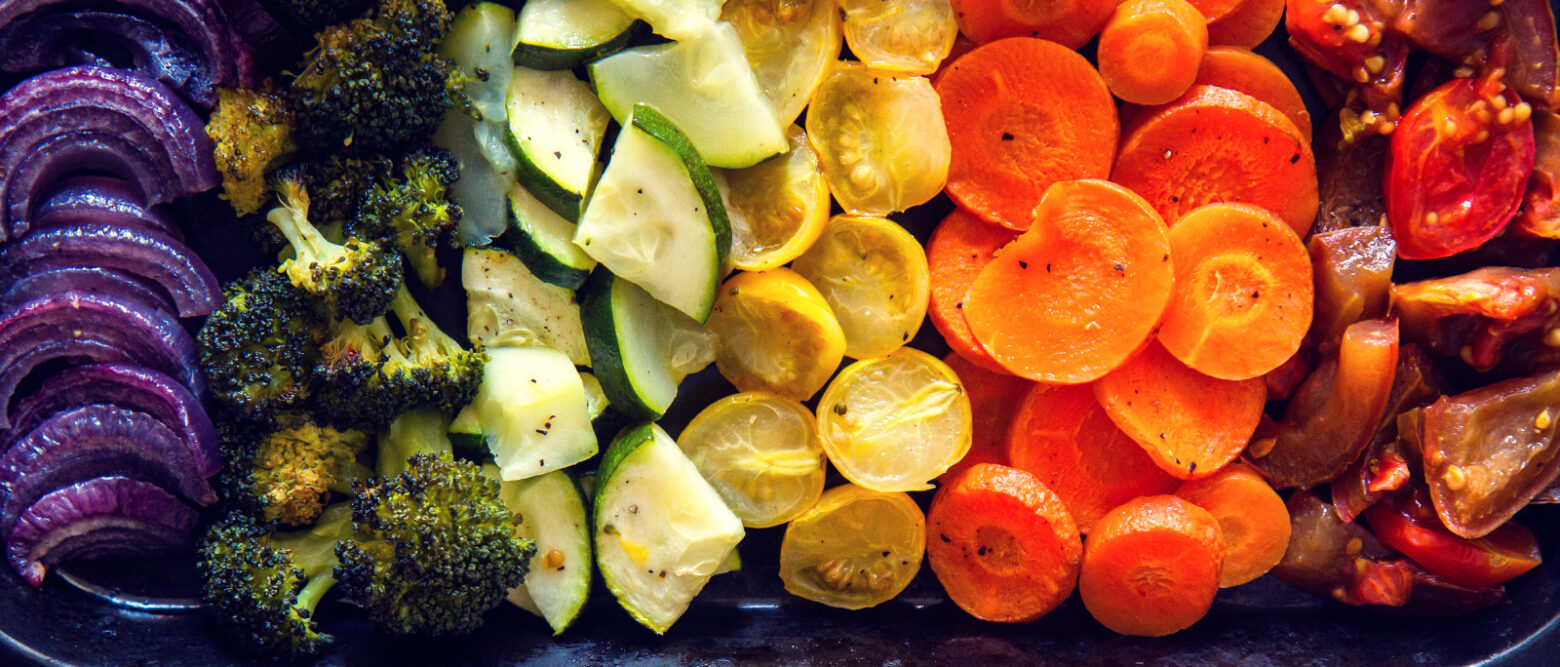 A variety of roasted vegetables arranged by color to make a rainbow