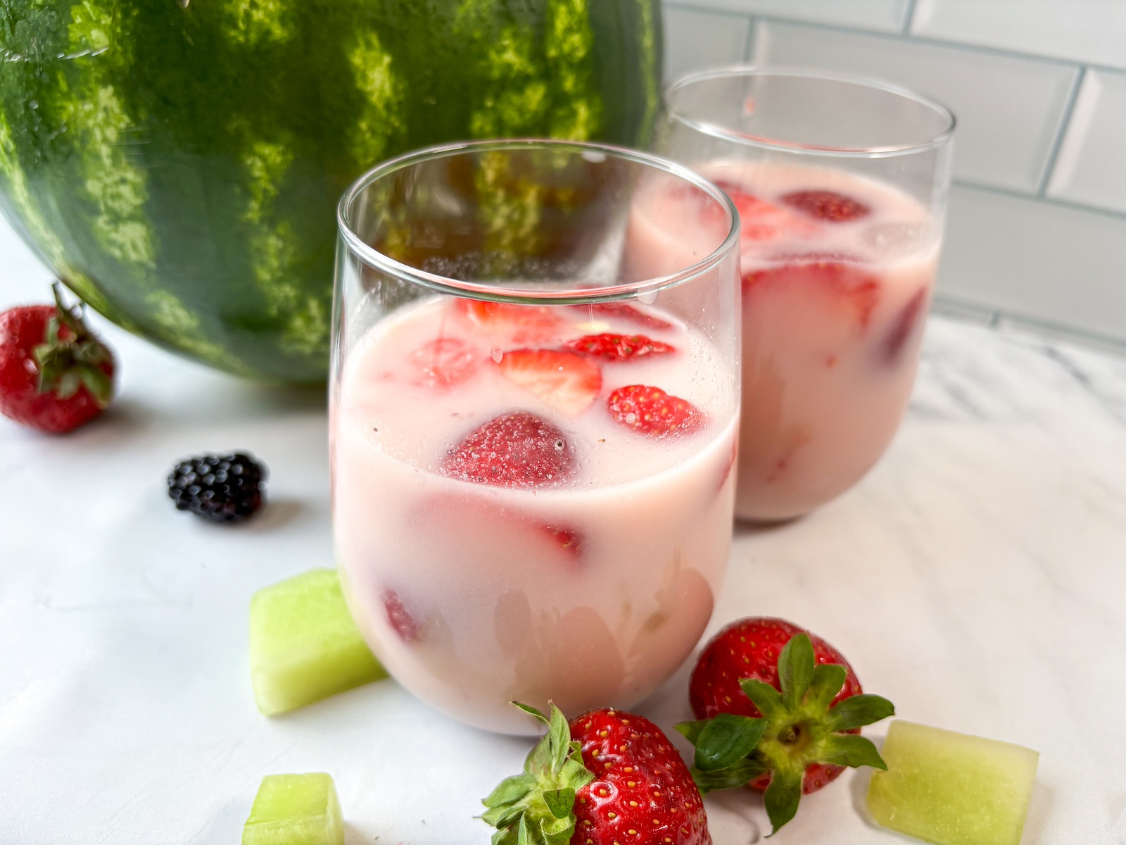 Subak-Hwachae in a glass in front of a watermelon punch bowl.