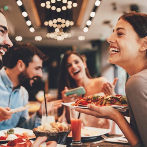 A happy group of people eating healthy food at a restaurant.