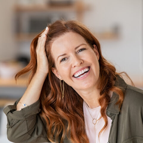 A beautiful smiling healthy woman brushes her hair back