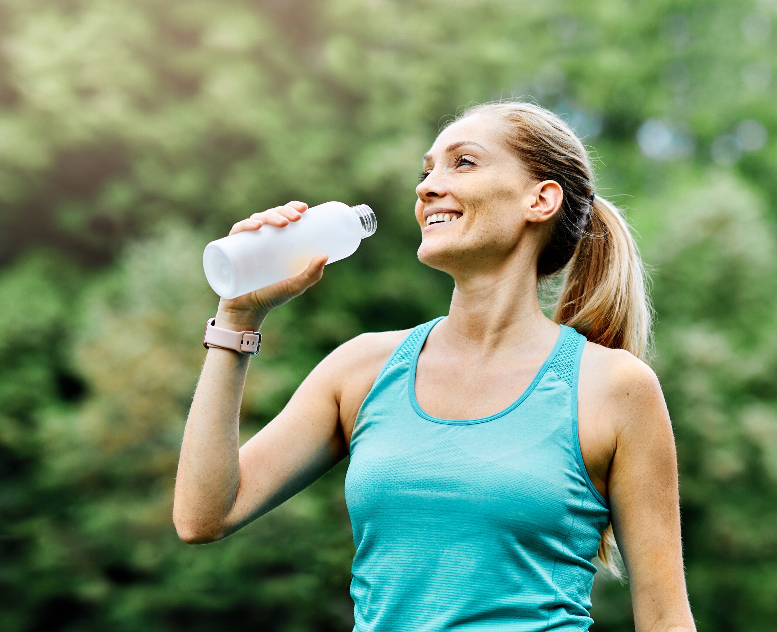 A sporty middle-aged woman drinks water after exercise to help her recover.