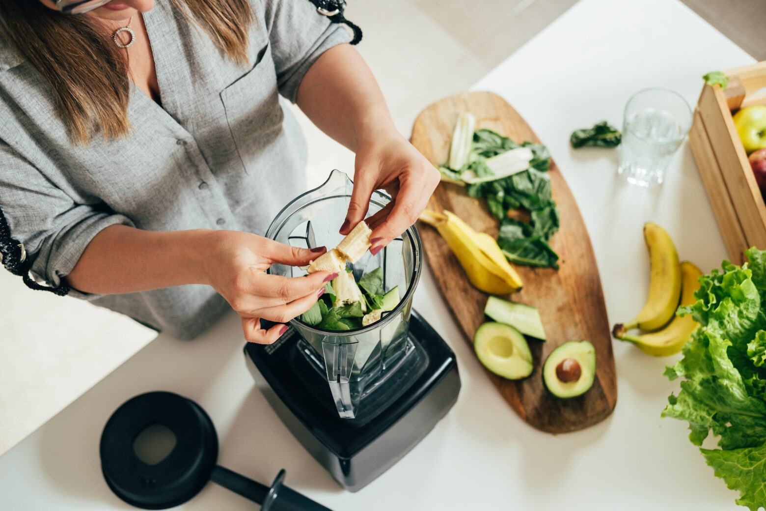 women putting fruit in blender